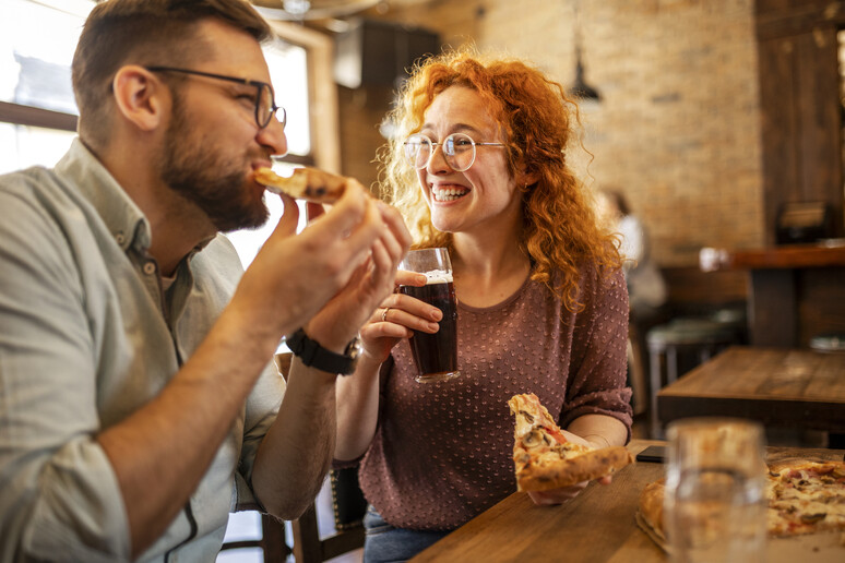 Un uomo e una donna sorridenti mangiano insieme foto iStock. - RIPRODUZIONE RISERVATA
