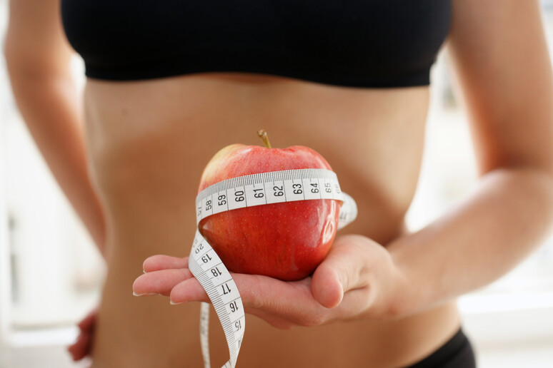 Una giovane donna magra con una mela in mano, un simbolo delle diete estreme foto iStock. - RIPRODUZIONE RISERVATA